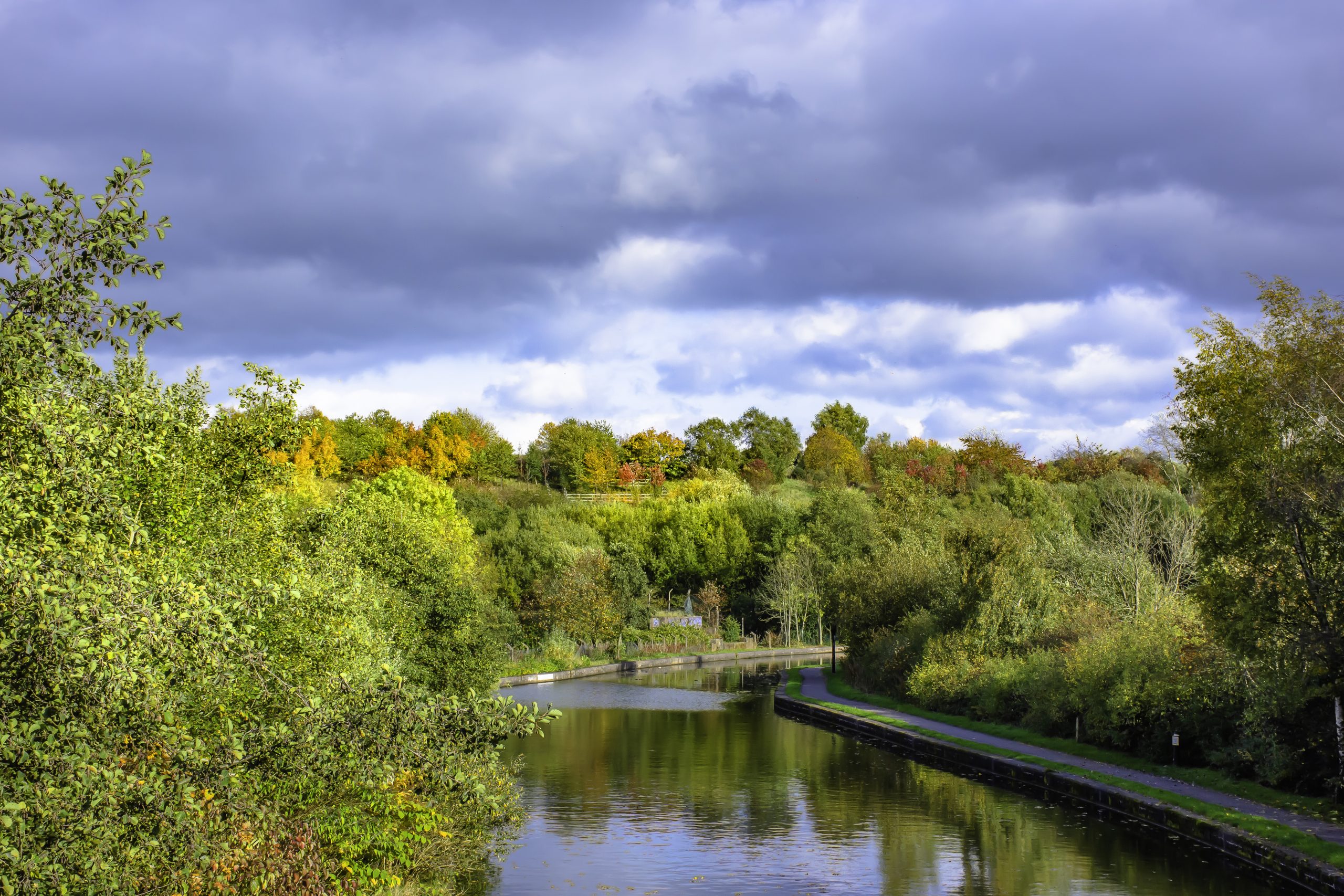 Autumn nature.Trees with leaves changing colour reflect in calm water of Trent and Mersey canal in central England.